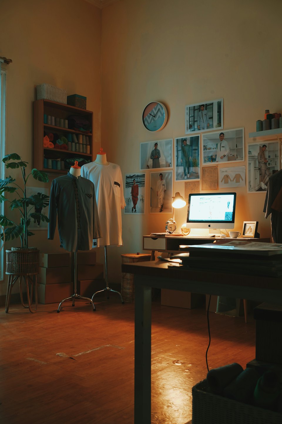 Mannequins stand in a tailoring workshop next to a desk.