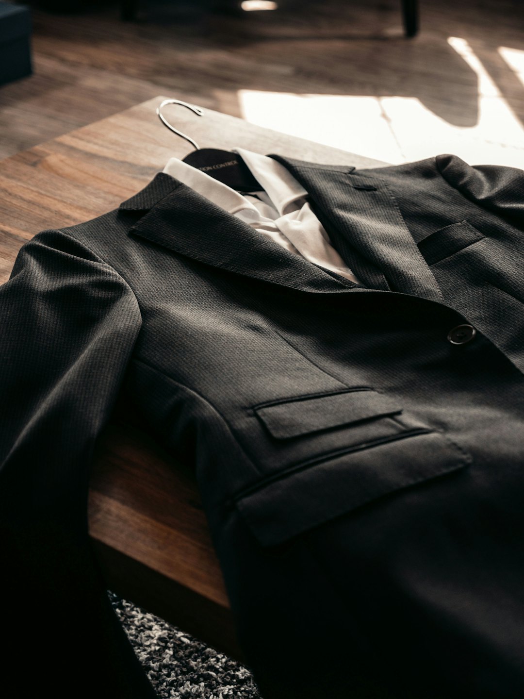 A suit jacket and white shirt on a wooden hanger.